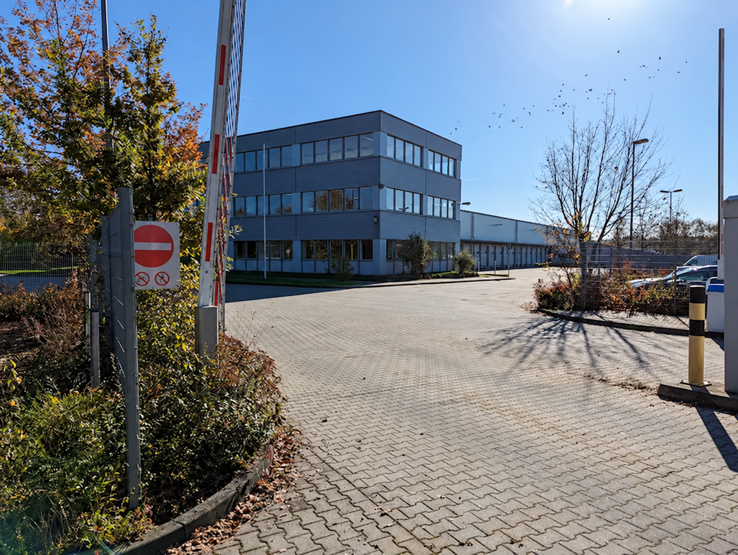 Einfahrt eines Logistikzentrums mit Verwaltungsgebäude und Lagerhalle; Beschilderung retuschiert